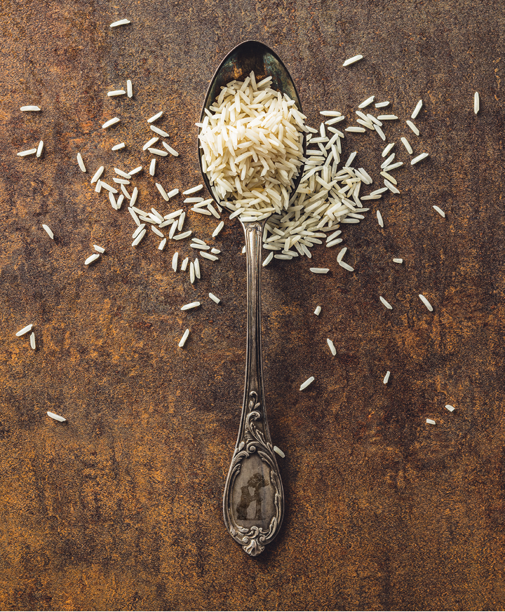 Uncooked indian long rice and spoon. Top view.
